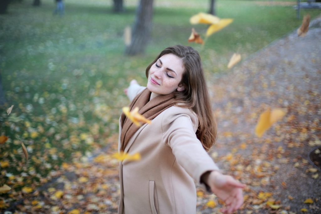 woman looking carefree with leaves falling around her