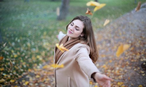 woman looking carefree with leaves falling around her