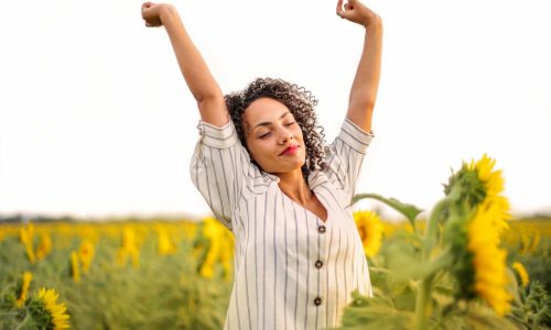 woman looking relaxed and carefree in field of sunflowers